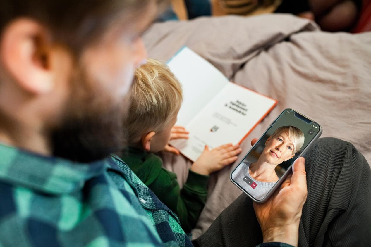 Isä asioi Mehiläisen etävastaanotolla puhelimellaan sairas lapsi sylissään.