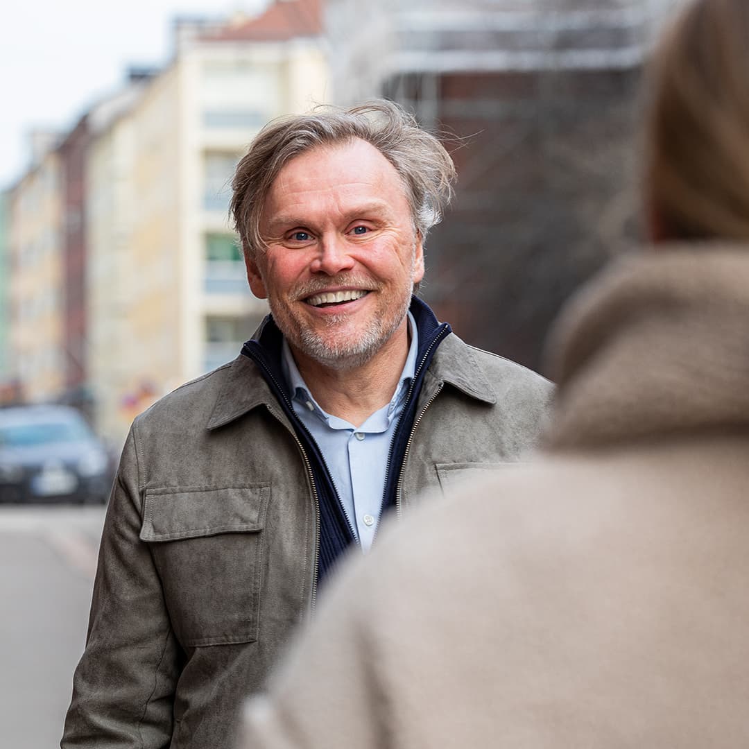 Keski-ikainen mies hymyilee kadulla kohdatessaan tutun vastaantulijan.
