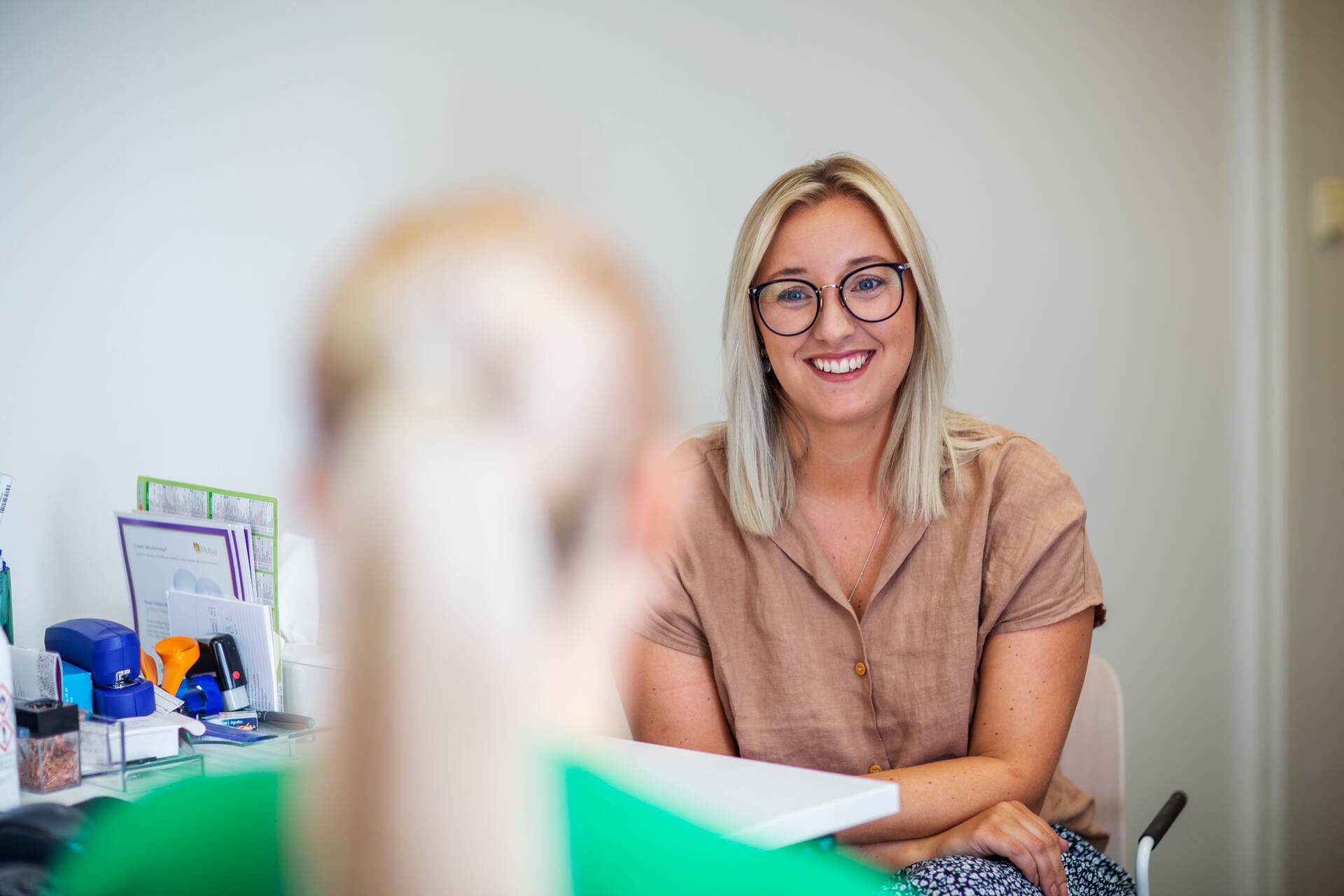 A person sitting and smiling at an appointment with a nurse.