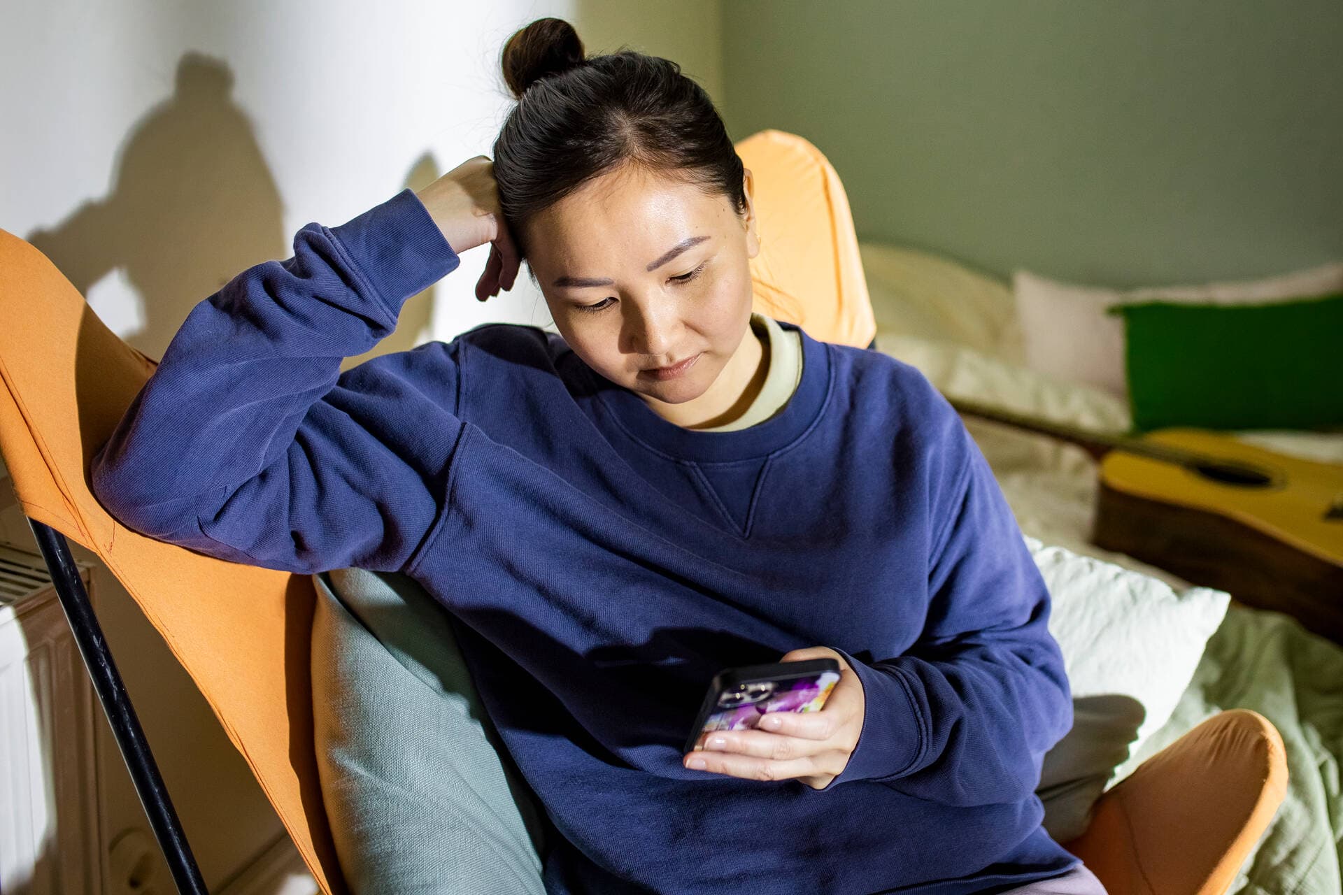 A person sitting on an armchair with a phone in their hand.