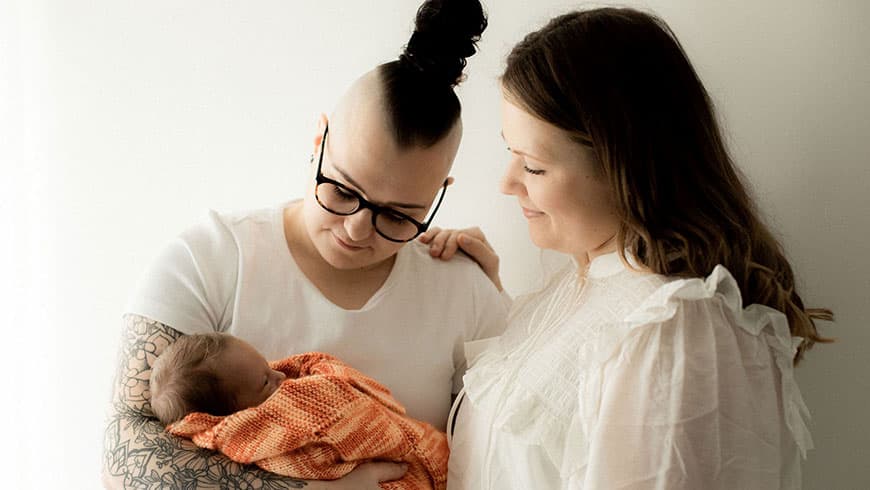 Aliisa ja Essi pitelevät yhteistä vauvaansa sylissaan.