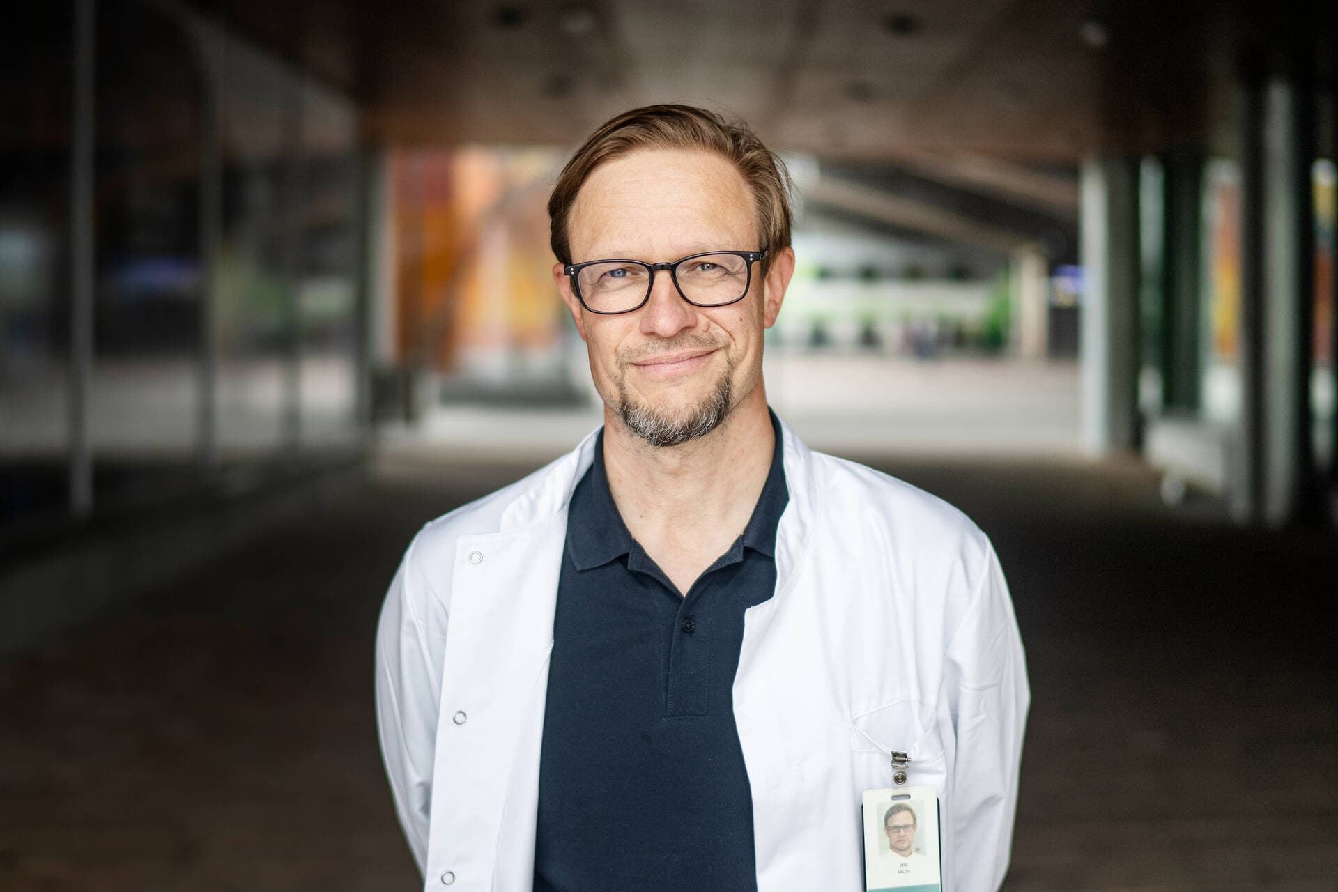 Mieslääkäri poseeraa kameraan hymyillen lääkärikeskuksen ulkopuolella.