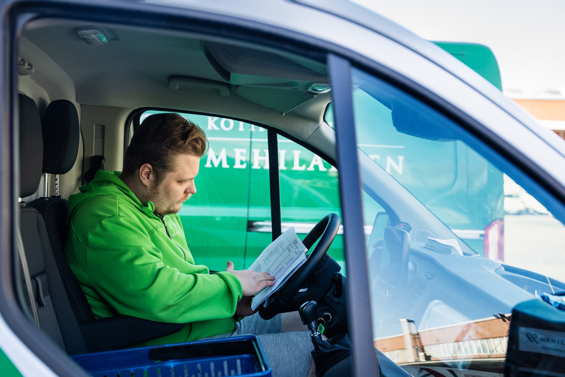 Mehiläisen ateriapalveluiden Anton tarkastamassa päivän tilauslistaa autossa.