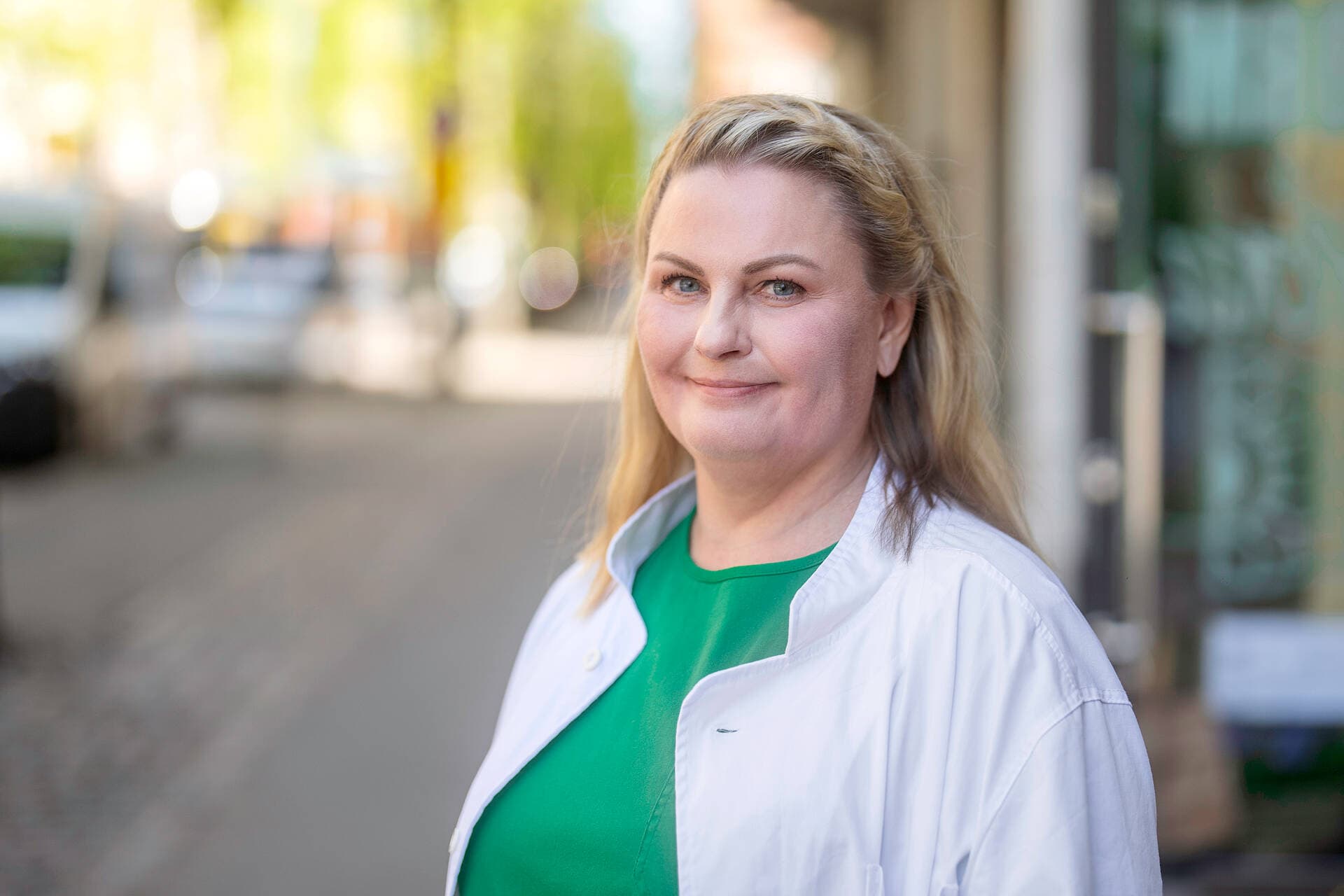 Vaihdevuosioireiden hoitoa tarjoava gynekologi seisoo ulkona lääkärikeskuksen edessä.