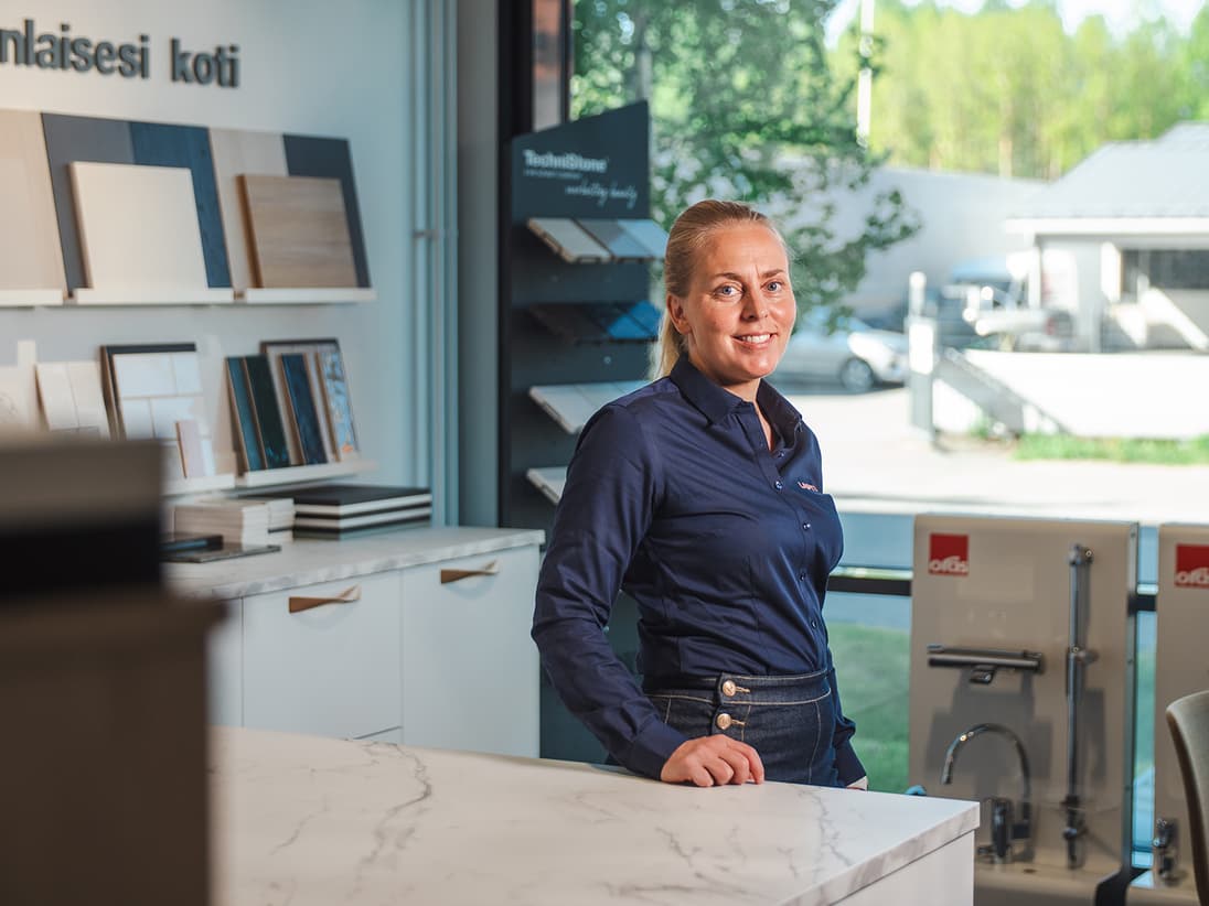 Riikka Säkkinen, HR Director of Rakennusliike Lapti, stands in a commercial space, smiling and looking at the camera.