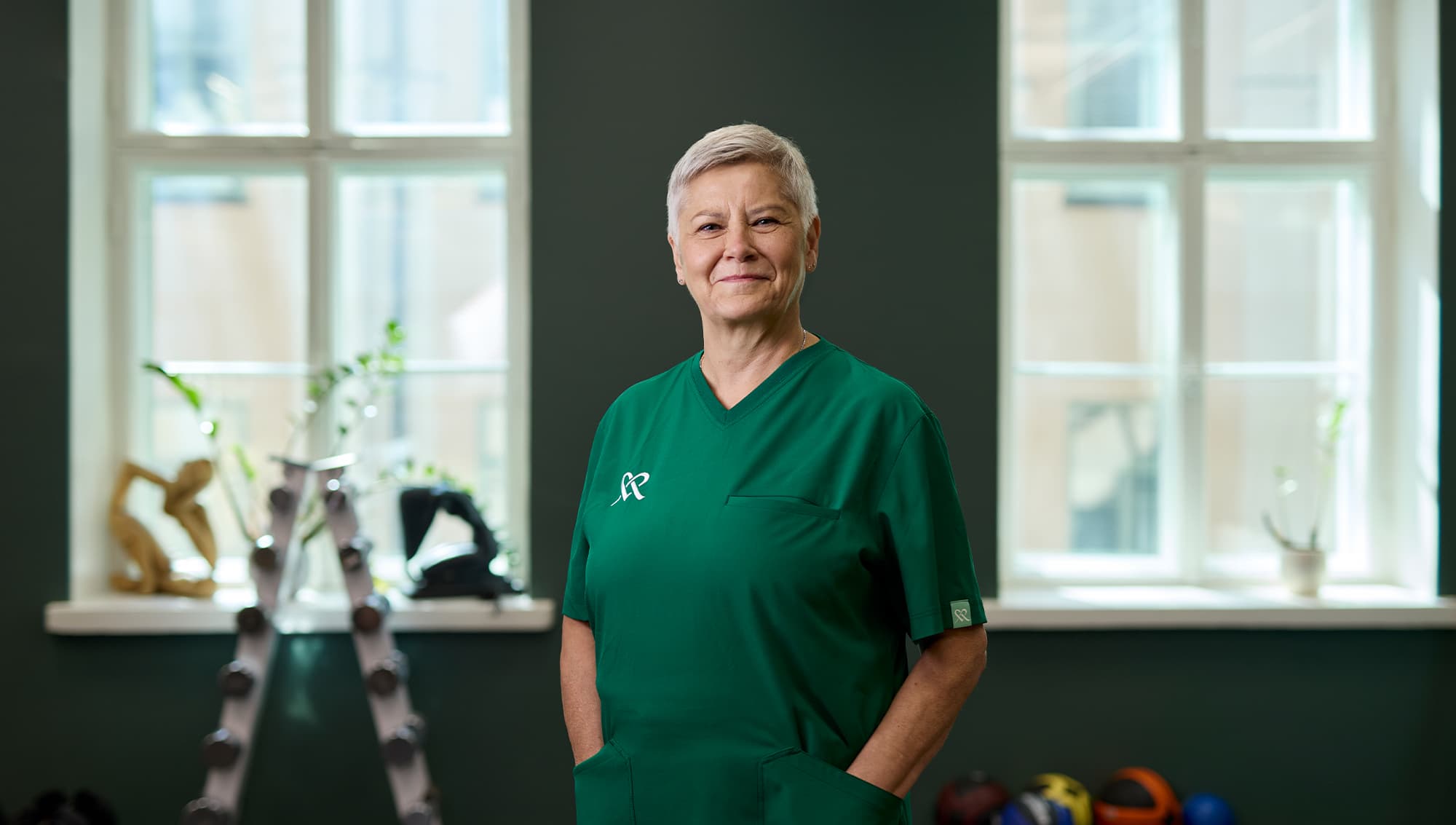 Mehiläisen asiantuntija seisoo yksikön huoneessa ja katsoo hymyillen kameraan