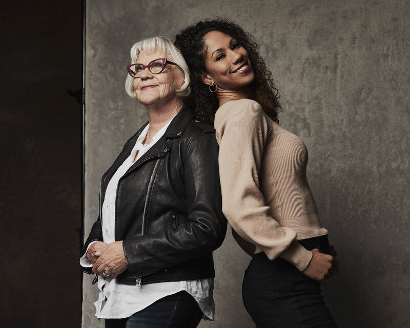 Iäkkäämpi ja keski-ikäinen nainen nojaavat toistensa selkää vasten.