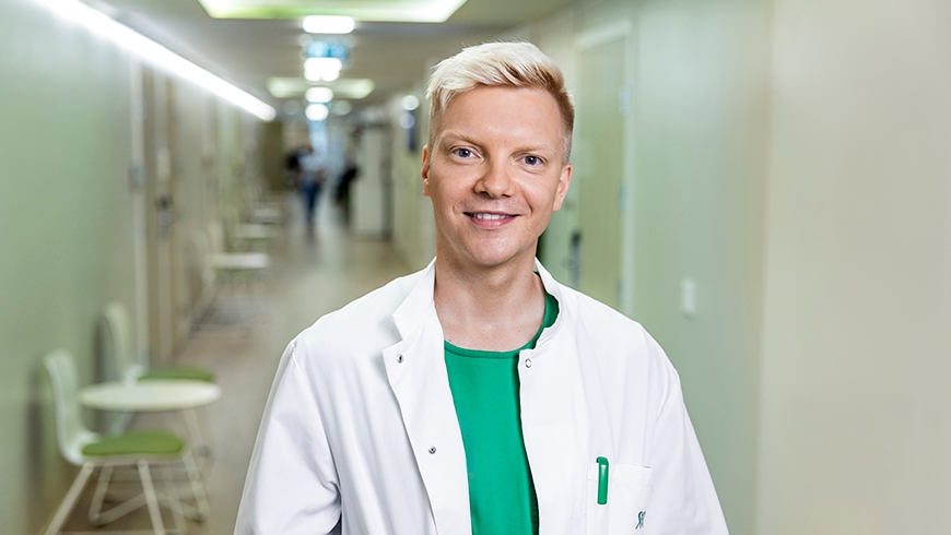 Mehiläisen yleislääkäri Niko hymyilee iloisesti lääkärikeskuksen käytävällä.